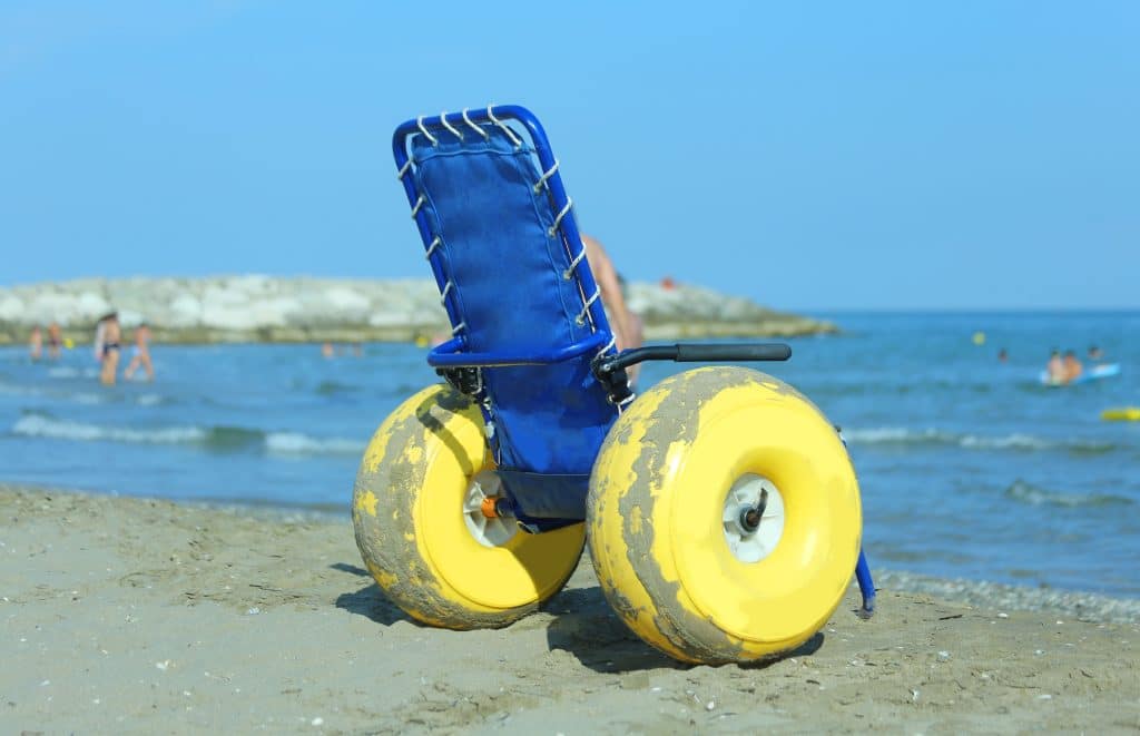 Special wheelchair with big yellow inflatable wheels to bring disabled people inside the water