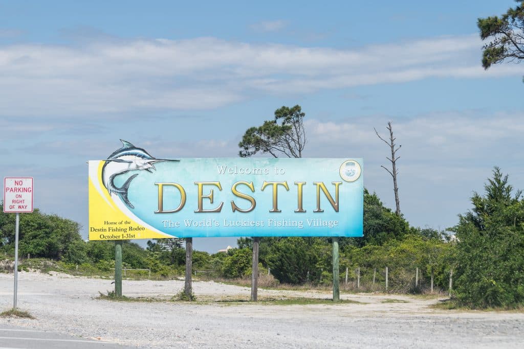Destin, USA - April 24, 2018: Road sign, billboard with Welcome to Destin the World's luckiest fishing village in Florida Panhandle